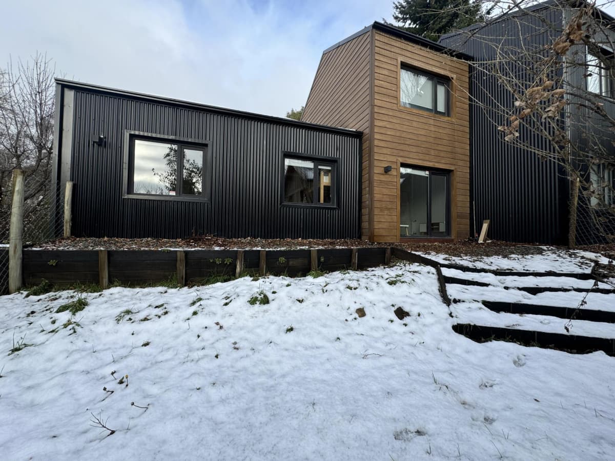 Vivienda a medida terminada en Ushuaia, revestimiento metálico oscuro y frente de madera